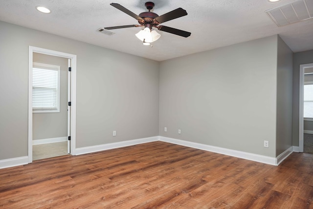 spare room with hardwood / wood-style flooring, a textured ceiling, and a wealth of natural light