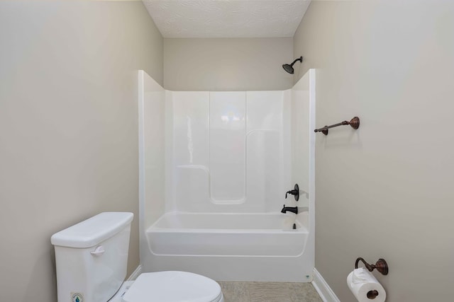 bathroom featuring bathing tub / shower combination, a textured ceiling, and toilet