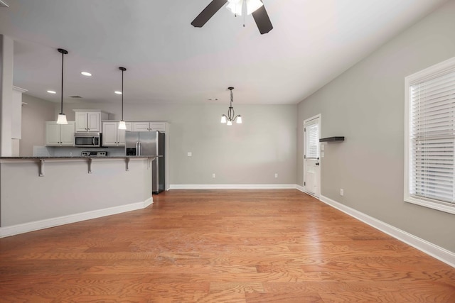 unfurnished living room featuring light hardwood / wood-style floors and ceiling fan with notable chandelier