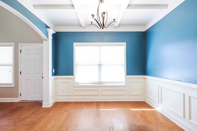 unfurnished dining area with beamed ceiling, an inviting chandelier, light hardwood / wood-style flooring, and coffered ceiling