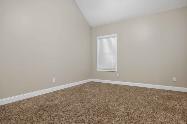 carpeted spare room with vaulted ceiling