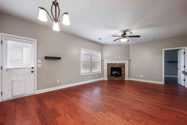 unfurnished living room with a fireplace, dark hardwood / wood-style flooring, and ceiling fan with notable chandelier