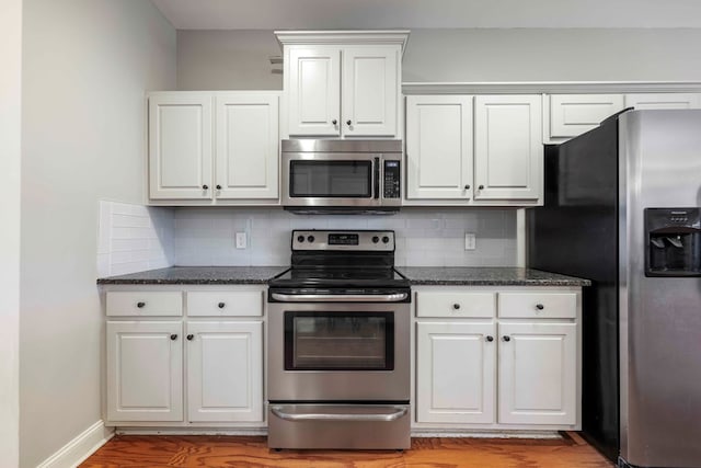 kitchen with white cabinets, light wood-type flooring, appliances with stainless steel finishes, and tasteful backsplash