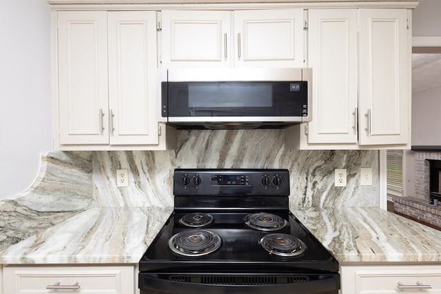 kitchen with white cabinets, backsplash, black electric range oven, and light stone countertops