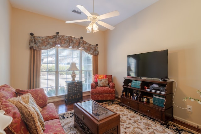 living room featuring baseboards, ceiling fan, visible vents, and wood finished floors