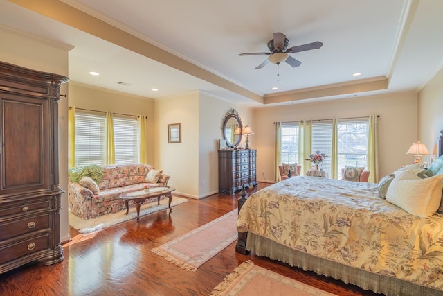 bedroom with dark wood-type flooring, a tray ceiling, crown molding, and baseboards