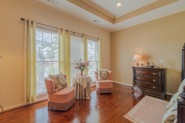 sitting room with wood finished floors, visible vents, baseboards, ornamental molding, and a tray ceiling