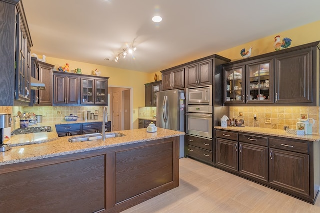 kitchen featuring dark brown cabinets, appliances with stainless steel finishes, a sink, and under cabinet range hood