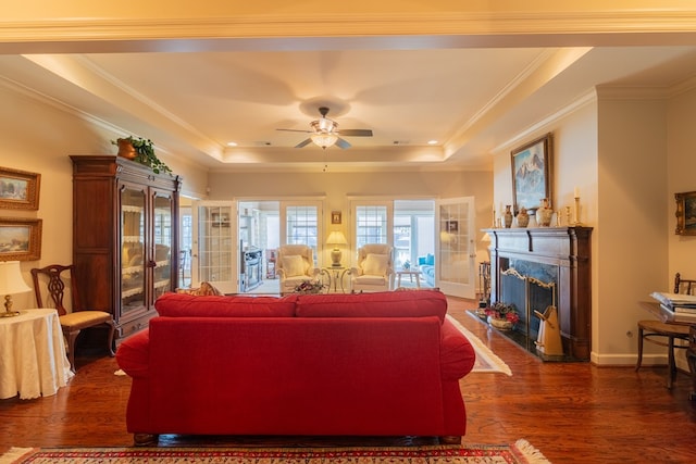 living room featuring dark wood-style floors, a tray ceiling, crown molding, and a high end fireplace