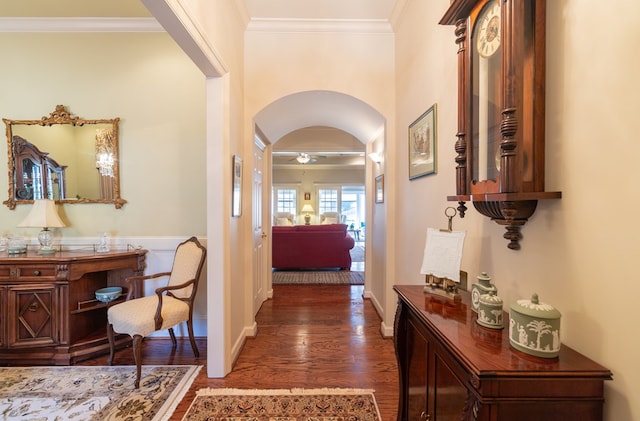 corridor featuring arched walkways, ornamental molding, a wainscoted wall, and wood finished floors