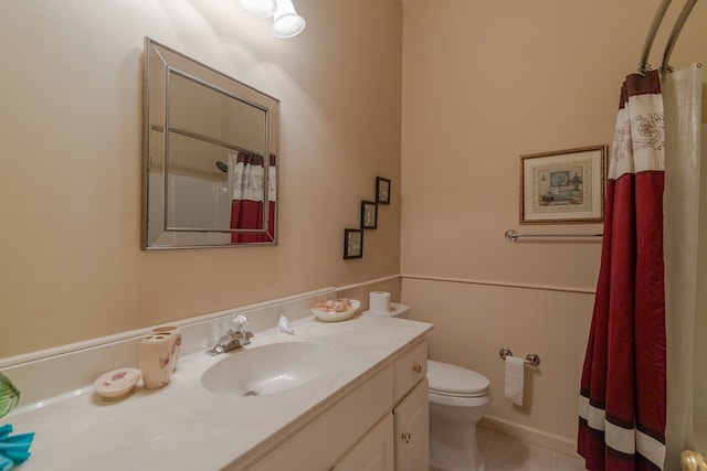 bathroom featuring tile patterned flooring, toilet, a wainscoted wall, a shower with shower curtain, and vanity