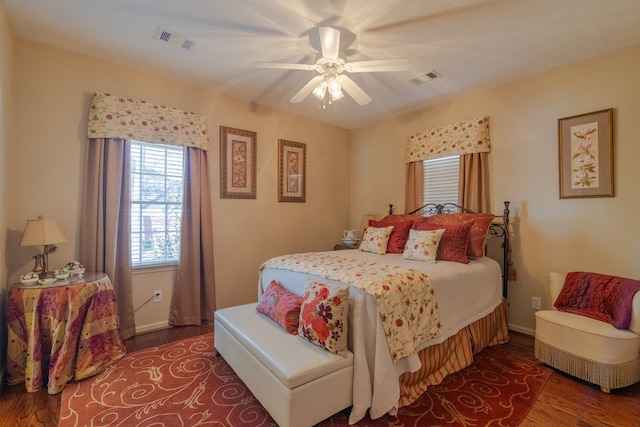 bedroom with baseboards, ceiling fan, visible vents, and wood finished floors