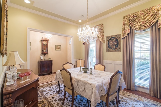 dining space featuring wainscoting, crown molding, a decorative wall, and an inviting chandelier