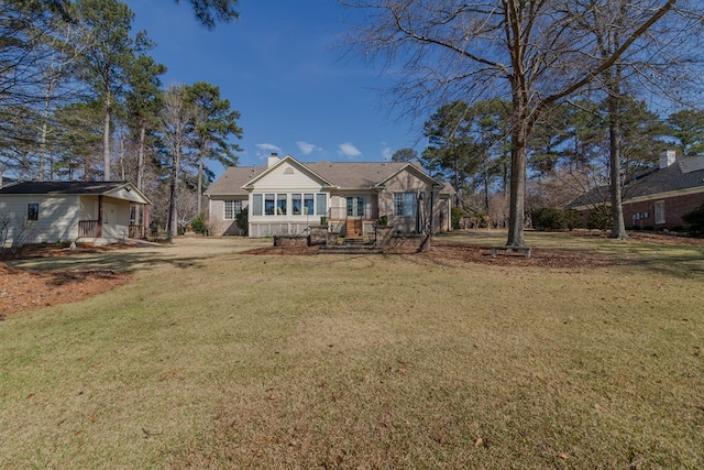 view of front of home with driveway, a front lawn, and a chimney