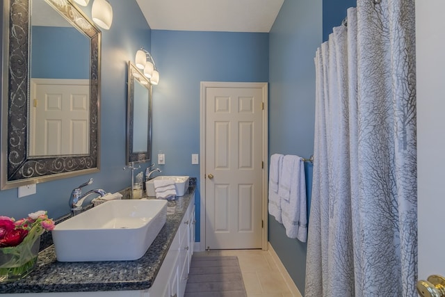 full bath featuring tile patterned floors, a sink, baseboards, and double vanity