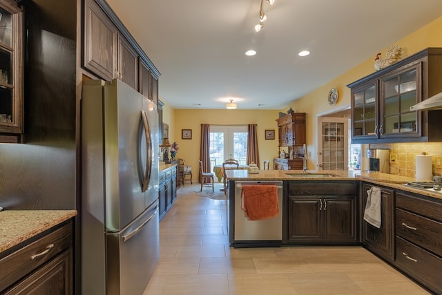 kitchen with dark brown cabinetry, a sink, stainless steel appliances, french doors, and backsplash