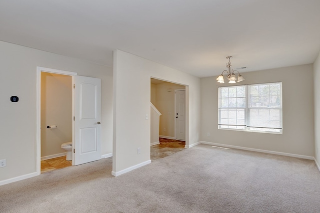 carpeted empty room with a notable chandelier