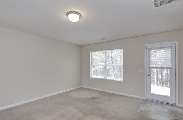 spare room featuring light carpet and a wealth of natural light