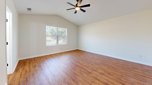 empty room with a ceiling fan, wood finished floors, visible vents, baseboards, and vaulted ceiling