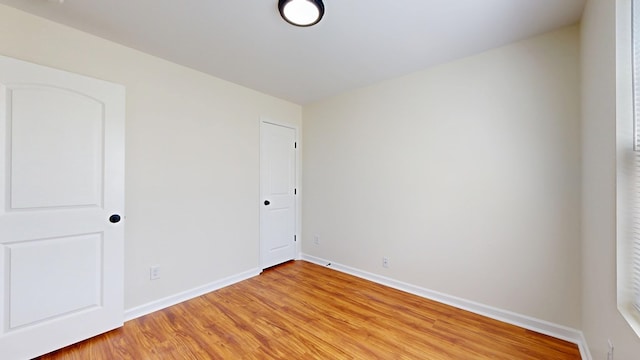 unfurnished room with light wood-type flooring and baseboards