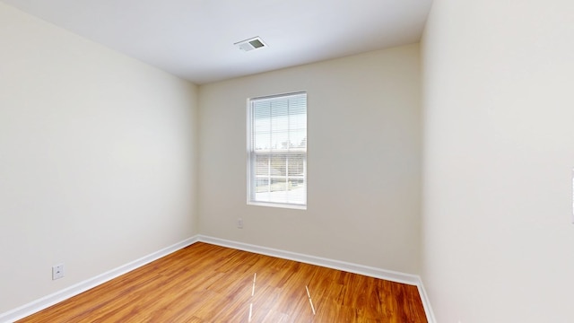 unfurnished room featuring light wood finished floors, visible vents, and baseboards