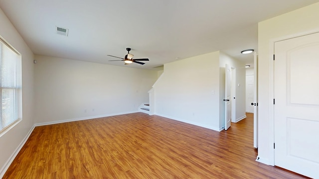 empty room with visible vents, light wood-style flooring, stairway, and baseboards