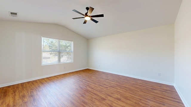 empty room with visible vents, lofted ceiling, wood finished floors, baseboards, and ceiling fan