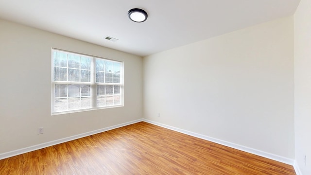 spare room with visible vents, light wood-style floors, and baseboards