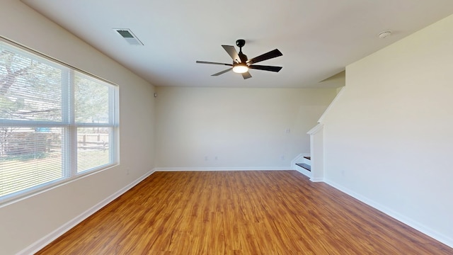 unfurnished living room with visible vents, ceiling fan, baseboards, stairs, and wood finished floors