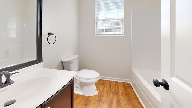 bathroom with toilet, wood finished floors, a bath, vanity, and a shower