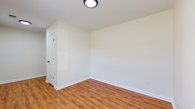 unfurnished room featuring visible vents, baseboards, and wood finished floors