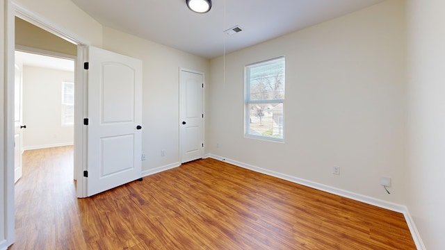 unfurnished bedroom featuring visible vents, baseboards, and wood finished floors