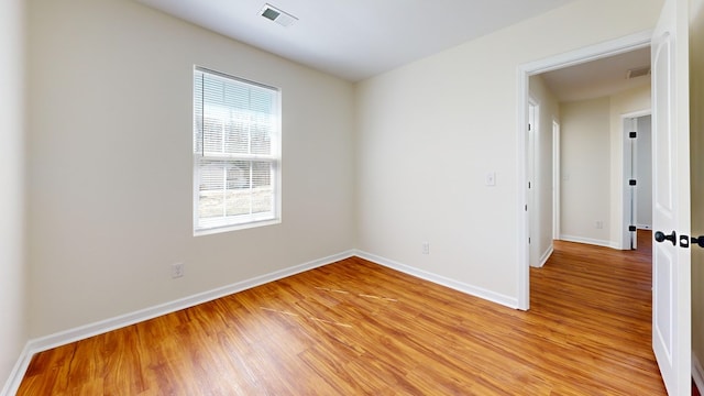 empty room featuring visible vents, light wood-style flooring, and baseboards