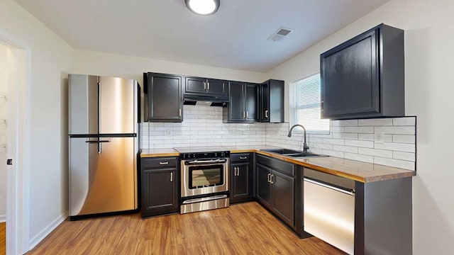 kitchen with visible vents, light wood-style flooring, a sink, under cabinet range hood, and stainless steel appliances