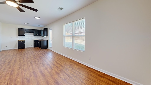 interior space with visible vents, baseboards, wood finished floors, a ceiling fan, and a sink