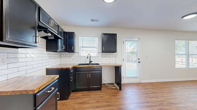 kitchen with visible vents, a sink, decorative backsplash, light wood-style floors, and butcher block counters