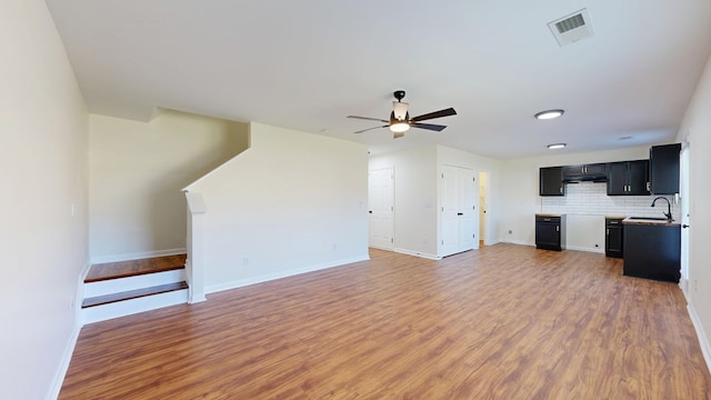 unfurnished living room with visible vents, a ceiling fan, a sink, light wood-style floors, and stairs