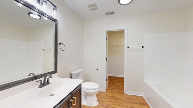 full bathroom with visible vents, a tub, toilet, wood finished floors, and vanity