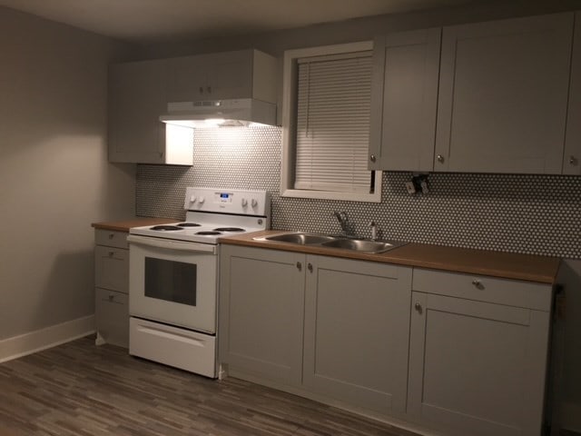 kitchen featuring backsplash, white cabinetry, white range with electric stovetop, and sink