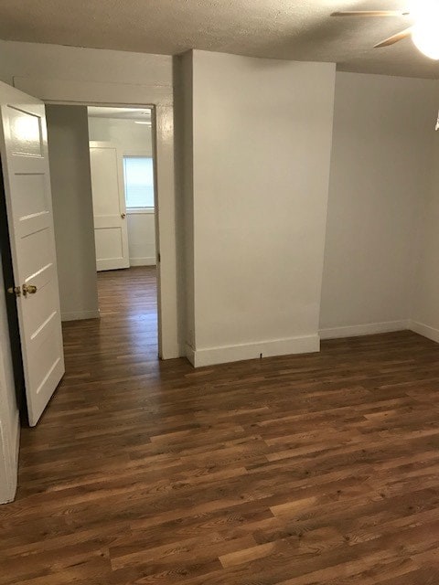 empty room with dark hardwood / wood-style floors, ceiling fan, and a textured ceiling