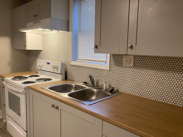 kitchen with backsplash, white range with electric cooktop, sink, and white cabinets