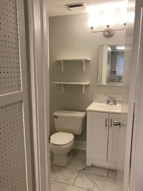 bathroom featuring vanity, a textured ceiling, and toilet