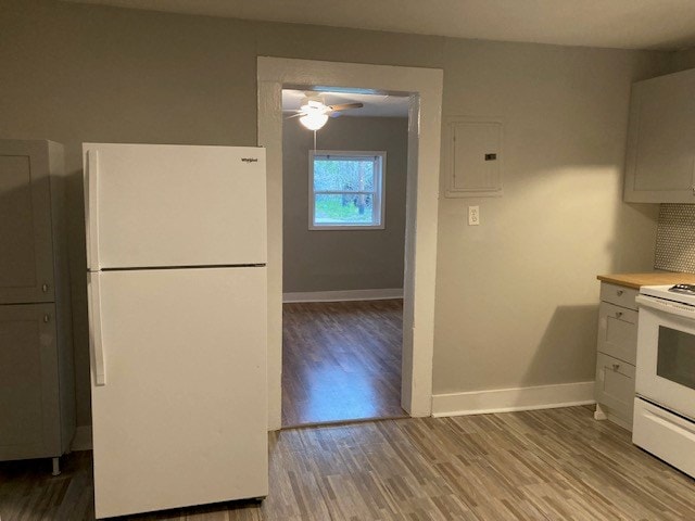 kitchen featuring white cabinets, light wood-type flooring, white appliances, and tasteful backsplash