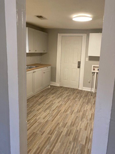 laundry room with cabinets, light wood-type flooring, and sink