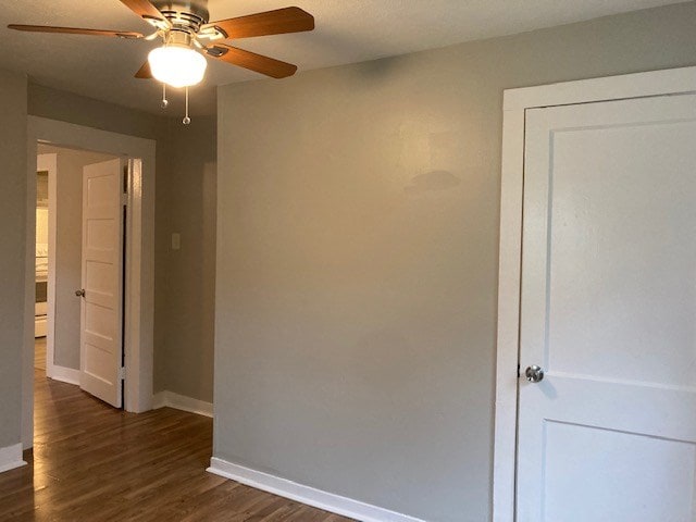 unfurnished room featuring ceiling fan and dark wood-type flooring