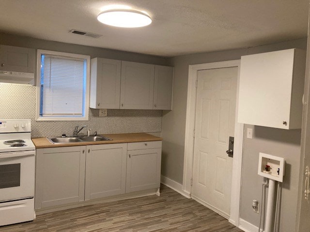 kitchen featuring exhaust hood, sink, decorative backsplash, white range with electric stovetop, and white cabinetry