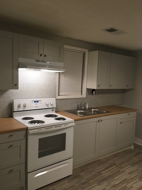 kitchen featuring hardwood / wood-style floors, backsplash, white range with electric cooktop, and butcher block counters