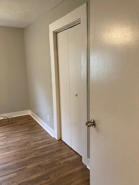 unfurnished bedroom with a closet, dark hardwood / wood-style flooring, and a textured ceiling