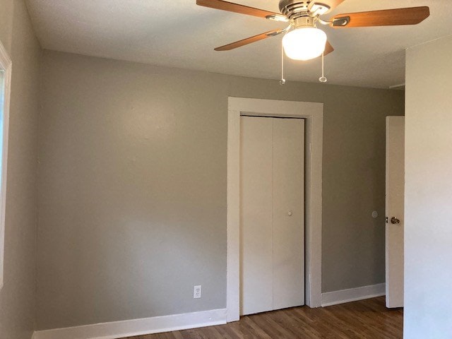 unfurnished bedroom featuring ceiling fan, dark wood-type flooring, and a closet