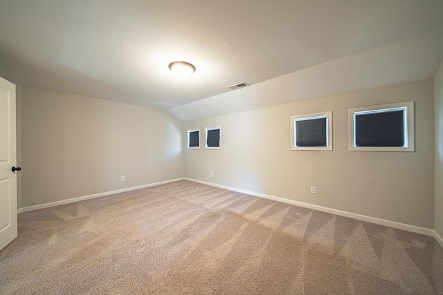 spare room with vaulted ceiling, carpet, visible vents, and baseboards